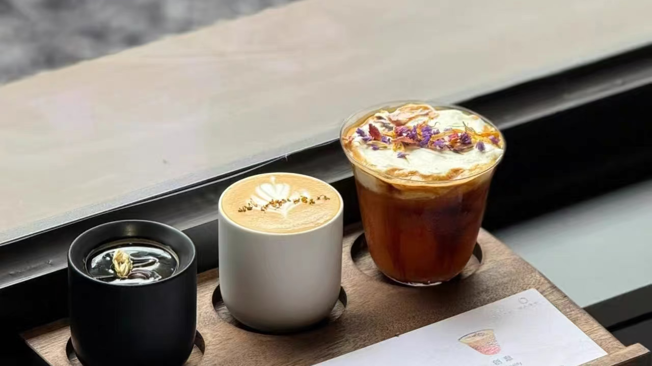 Three coffee drinks on a wooden tray with a blurred background